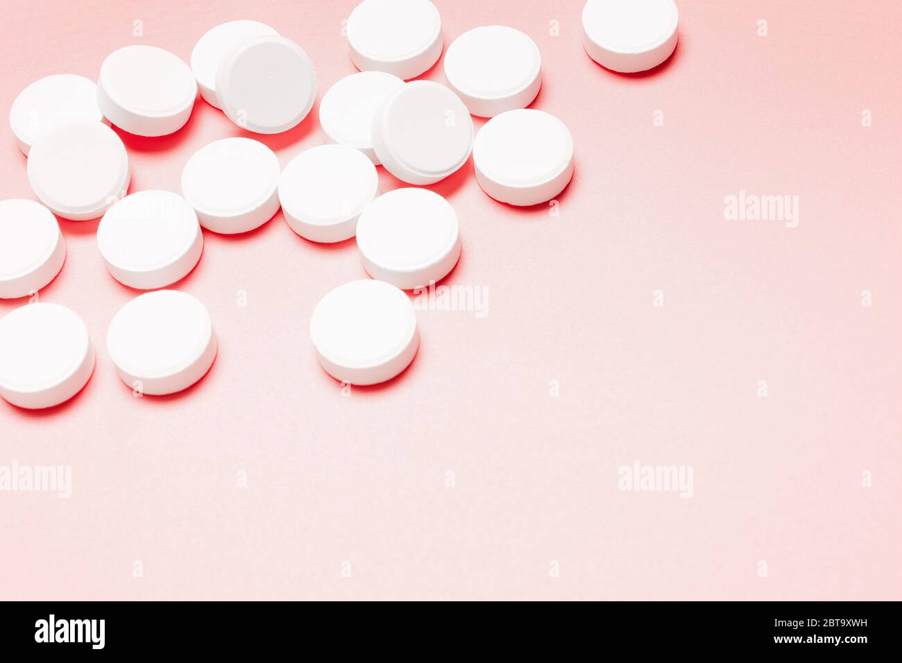 Pilules blanches, rondes sur fond rose. Le concept du traitement de la maladie, des soins de santé, de la santé des femmes. Banque D'Images