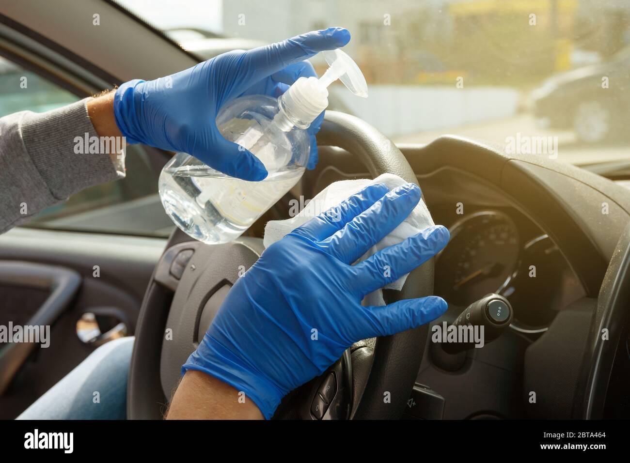 Désinfection automobile. Un homme en gants et un masque essuie le volant avec un chiffon désinfectant. Banque D'Images