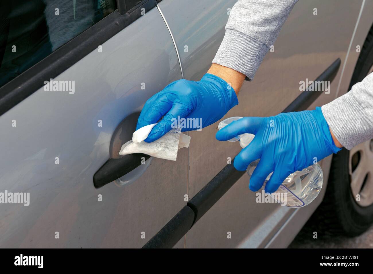 Désinfection automobile. Un homme en gants essuie la porte de la voiture avec un désinfectant. Banque D'Images