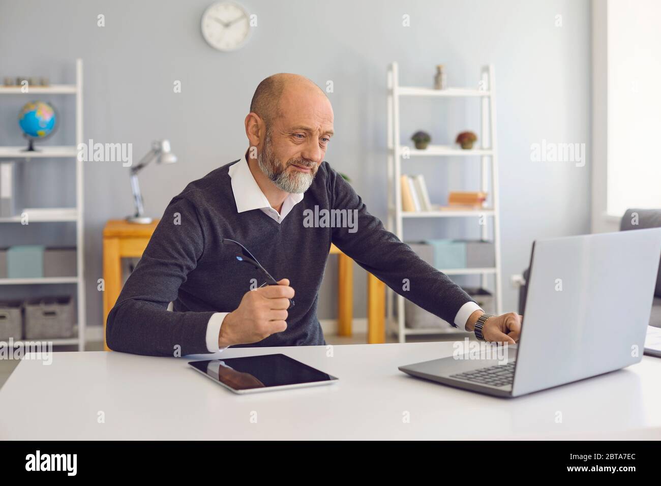 Un homme âgé travaille à domicile avec un ordinateur portable. Homme mature et confiant avec une barbe grise analyse une stratégie d'affaires à distance dirige une startup sitti Banque D'Images