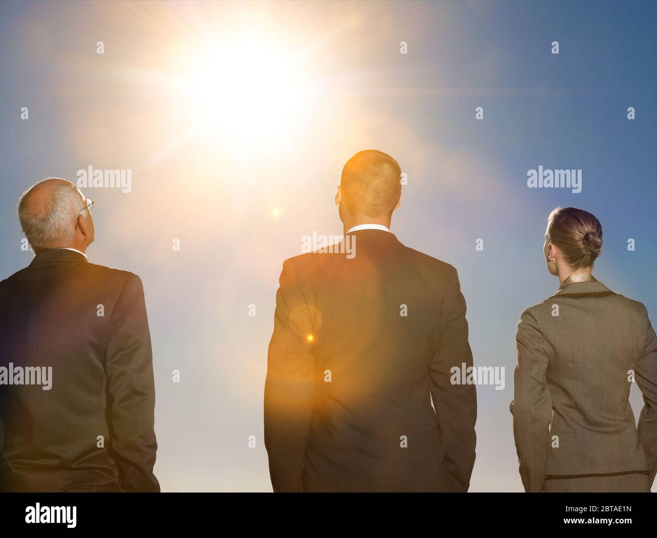 Photo isolée de la vue arrière de trois personnes d'affaires regardant le soleil Banque D'Images