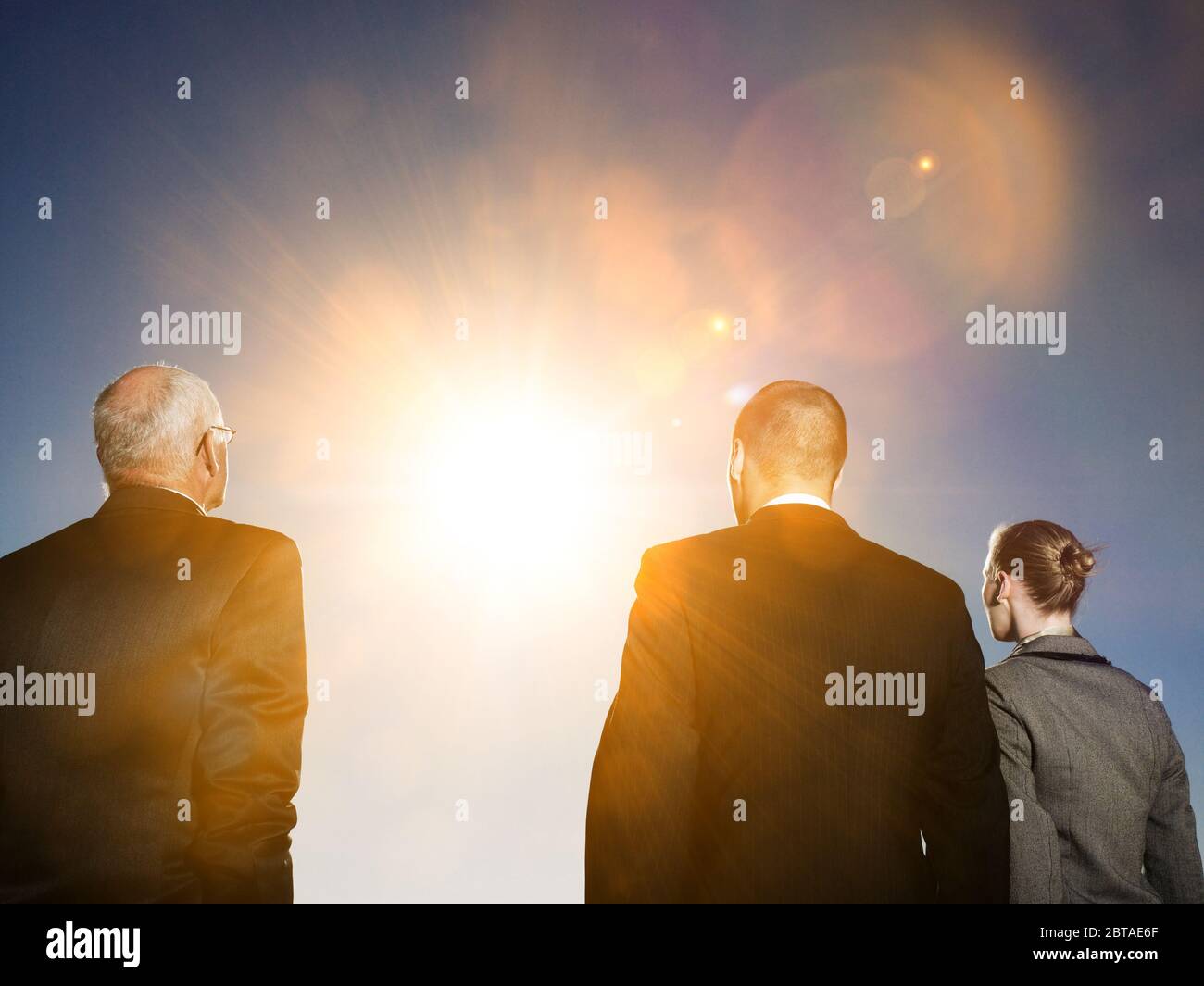 Photo isolée de la vue arrière de trois personnes d'affaires regardant le soleil Banque D'Images