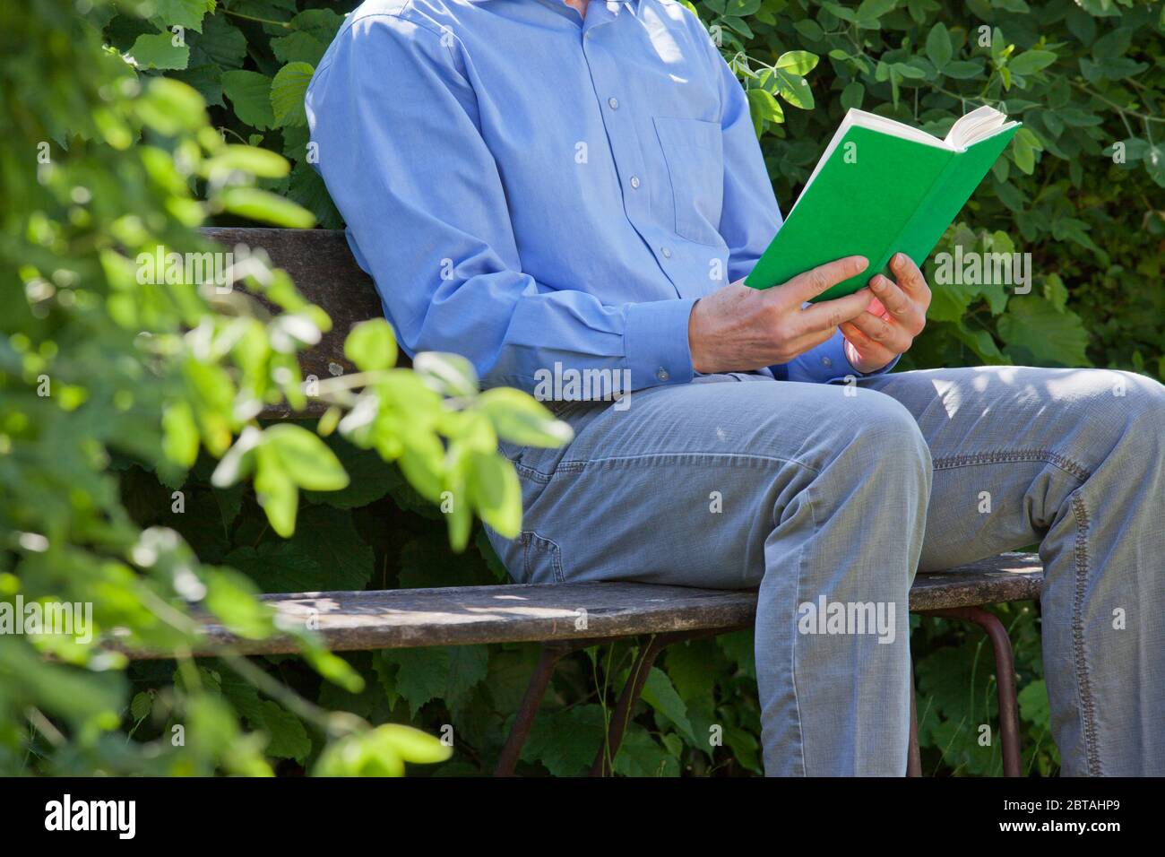 Homme d'affaires décontracté lisant un livre vert sur un banc de parc - se concentrer sur le livre vert Banque D'Images