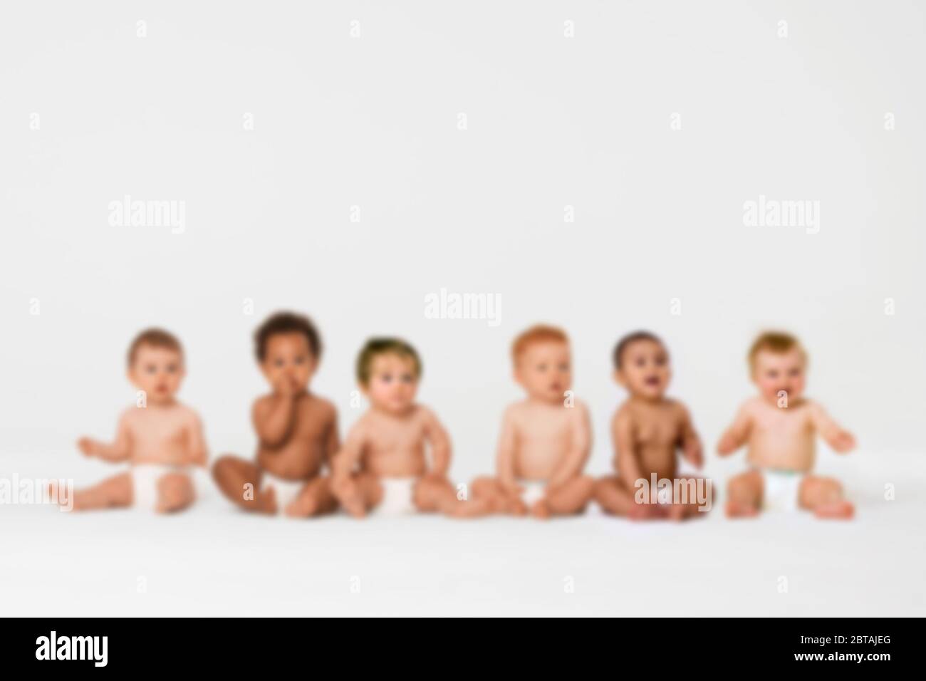 Photo floue de la rangée de six bébés ethniques multiples souriant en studio Banque D'Images