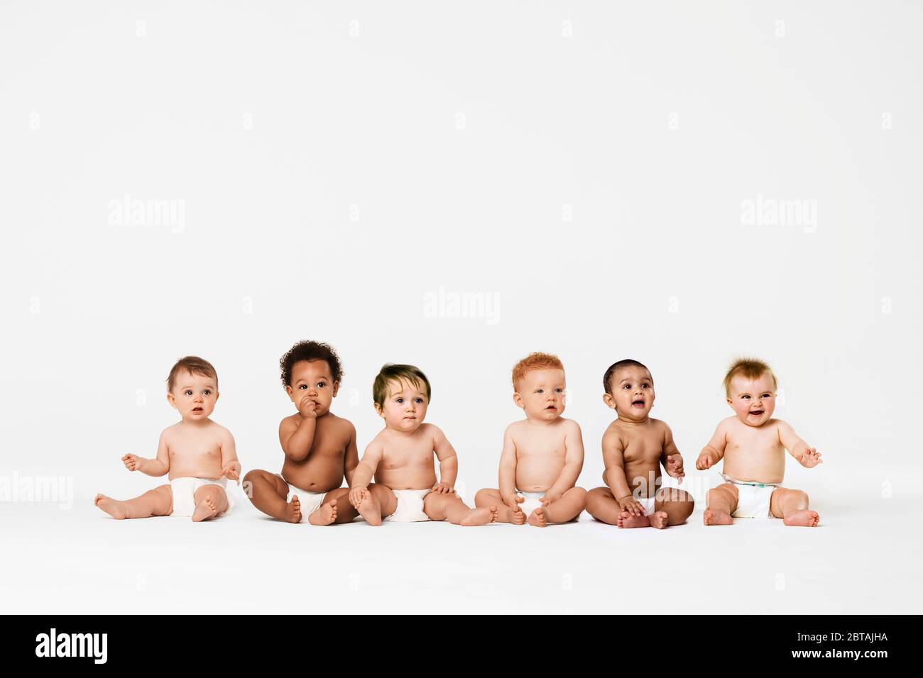 Rangée de six bébés multiethniques souriant en studio Banque D'Images