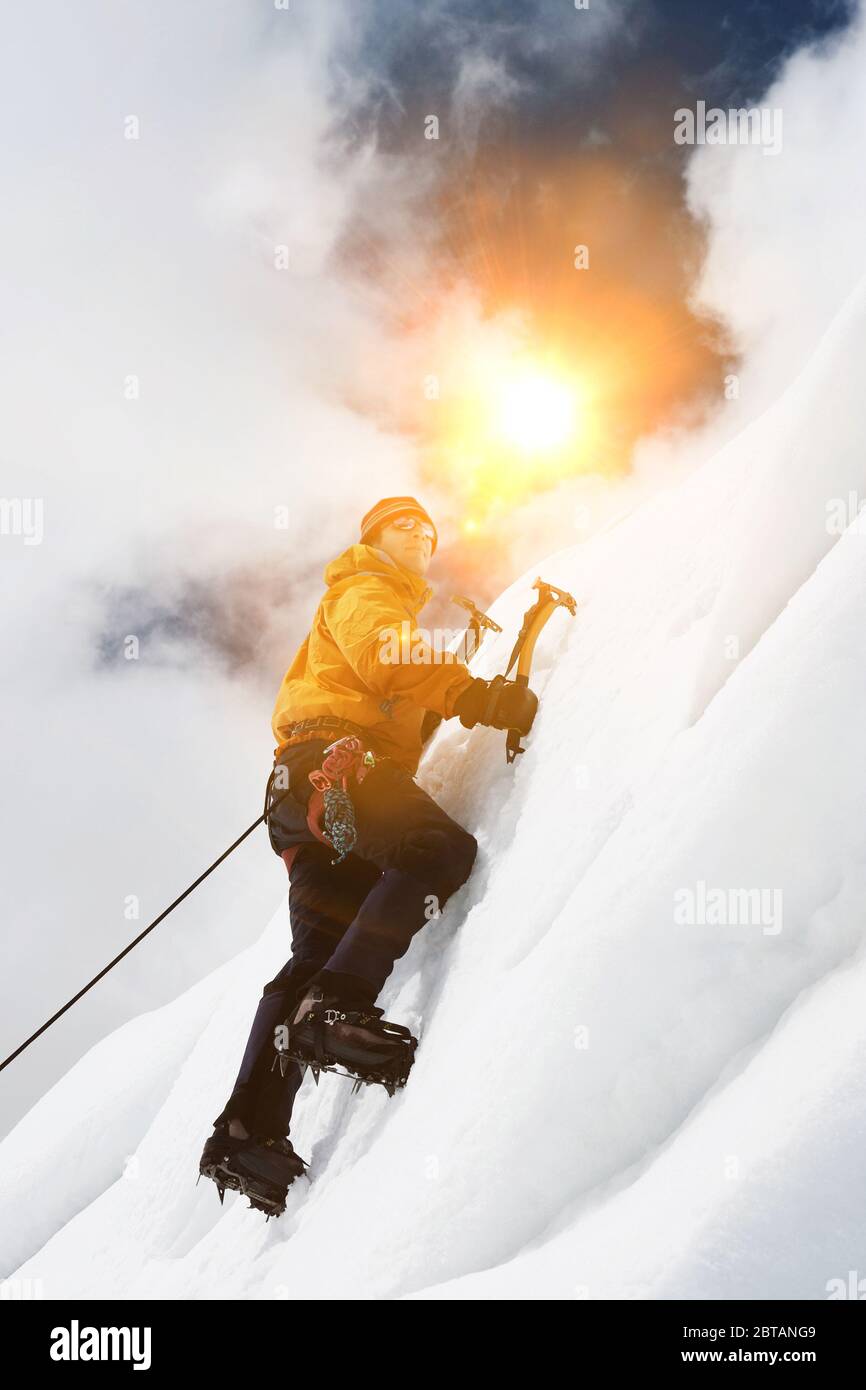 Grimpeur sur glace utilisant des haches pour grimper en montagne Banque D'Images