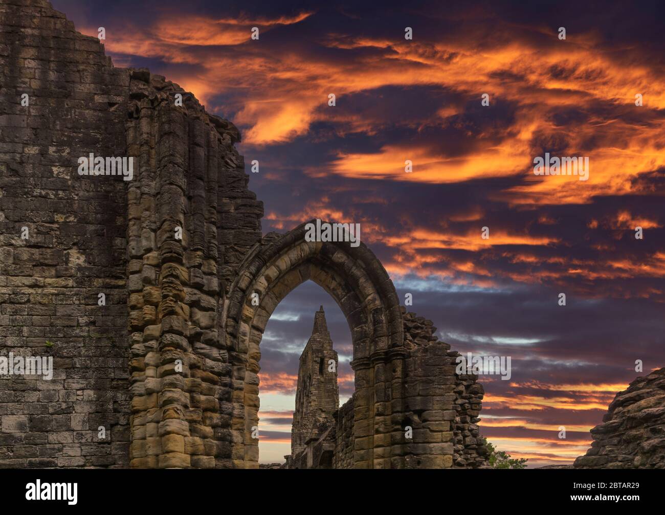 Vue à travers l'ancienne entrée en pierre des ruines anciennes du transept et le spectaculaire ciel de coucher de soleil à l'abbaye de Kilwinning en Écosse. Banque D'Images