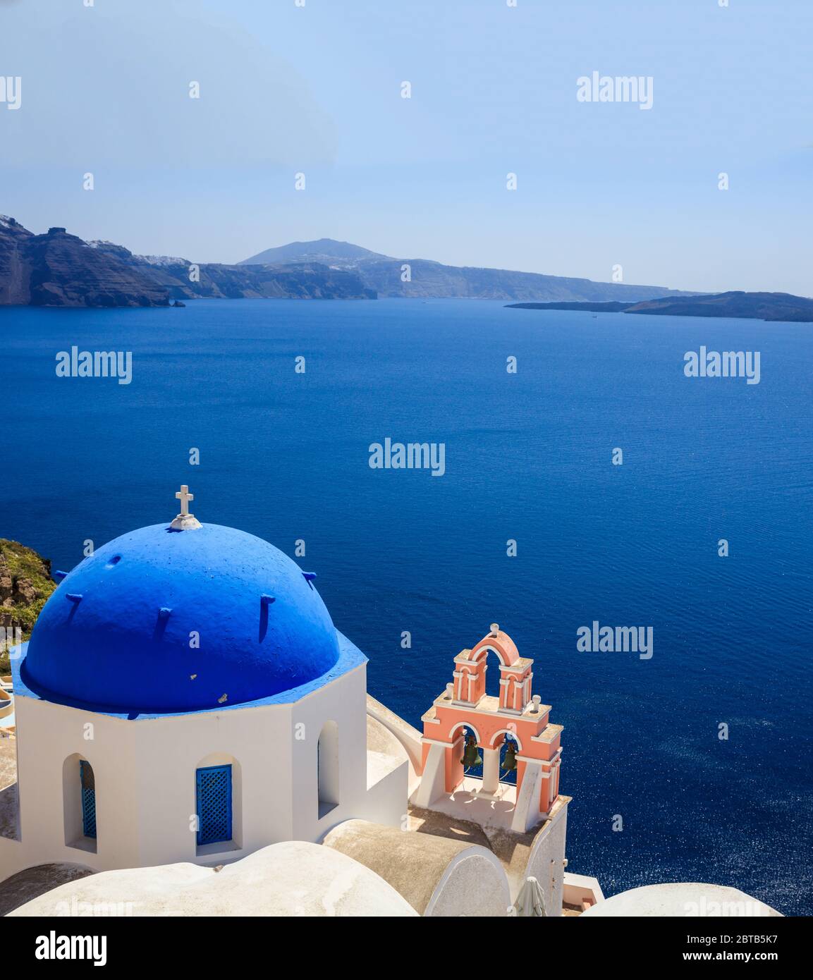 Île de Santorin, Grèce. Église orthodoxe blanche avec dôme bleu contre mer bleue calme et ciel clair fond, Oia village Banque D'Images