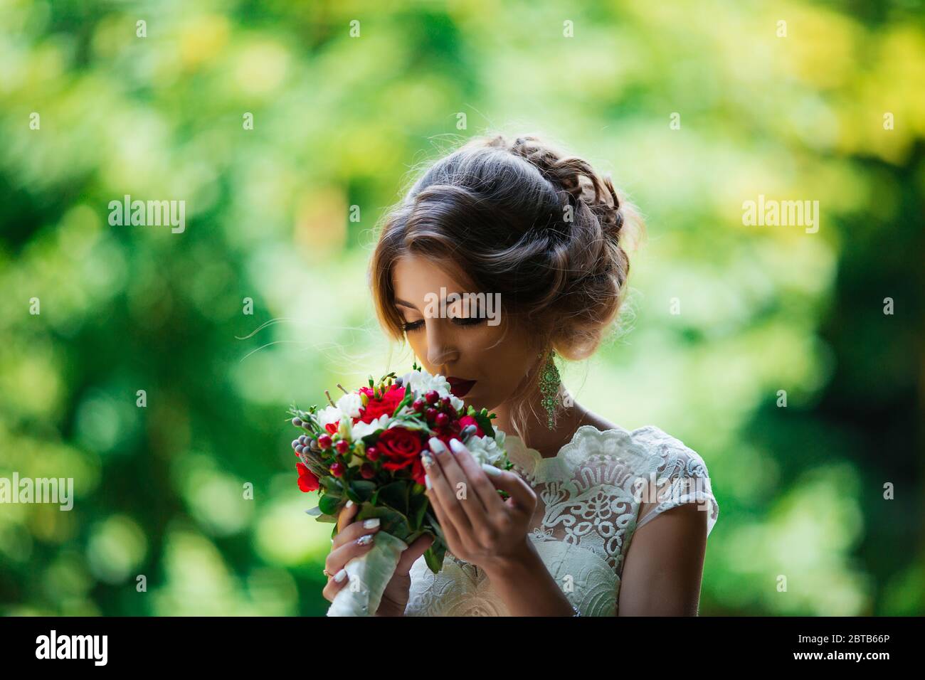 brunette mariée dans une robe de mariage et un bouquet au coucher du soleil dans le parc Banque D'Images