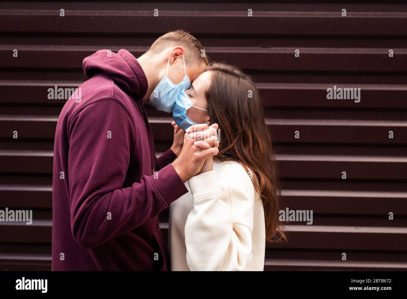 Couple en quarantaine essayant de baiser portant un masque . Concentrez-vous sur les mains Banque D'Images