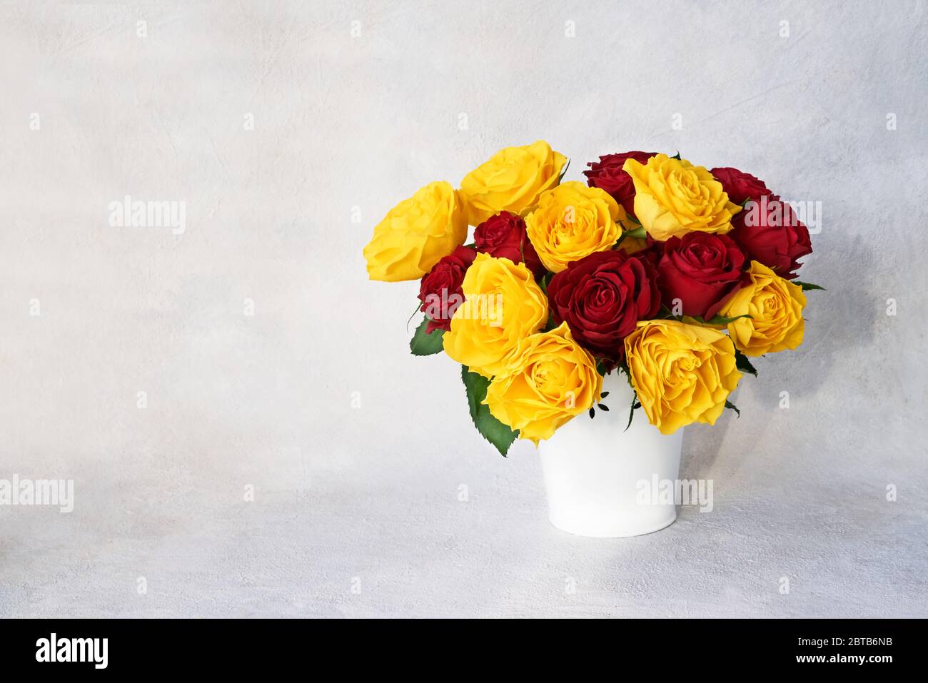 Bouquet de roses rouges et jaunes dans un vase blanc. Concept anniversaire, Fête des mères, Fête de la Saint-Valentin Banque D'Images