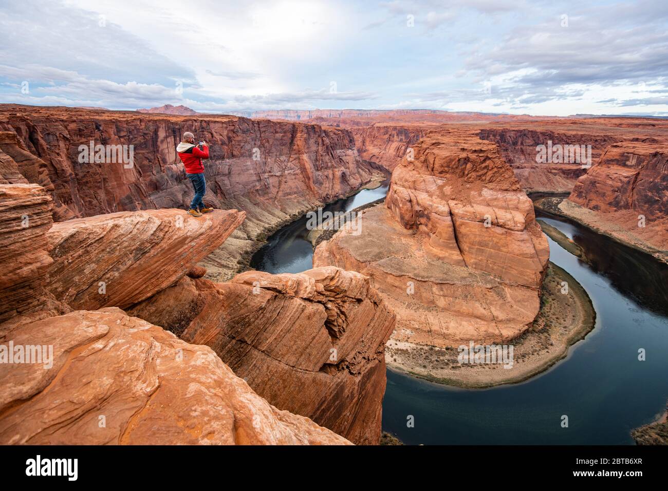 Homme assis sur une falaise au-dessus du fleuve Colorado dans le canyon Horseshoe Bend Banque D'Images