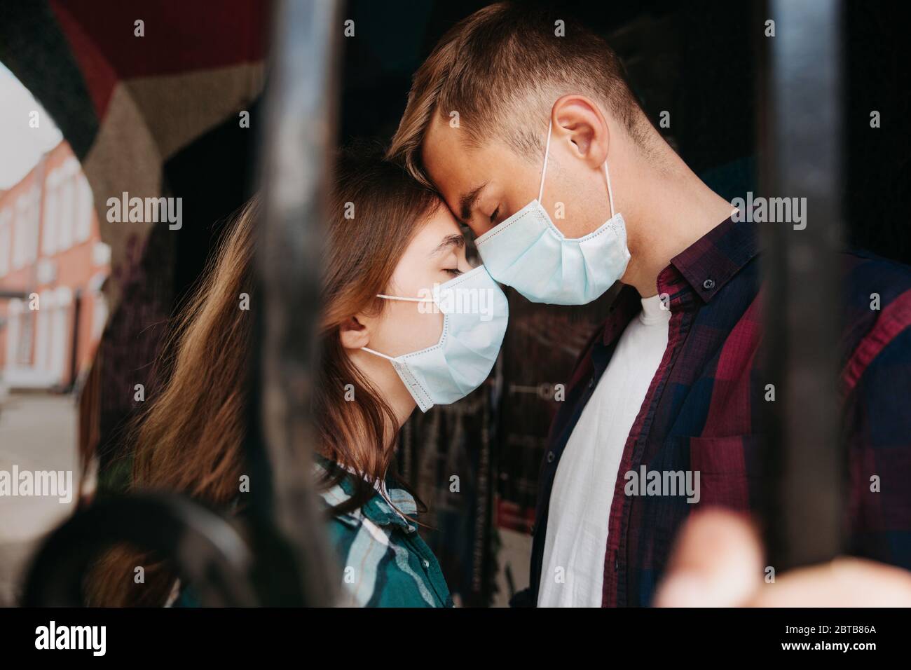 Couple amoureux, homme et femme s'embrassant dans un masque médical protecteur sur le visage Banque D'Images