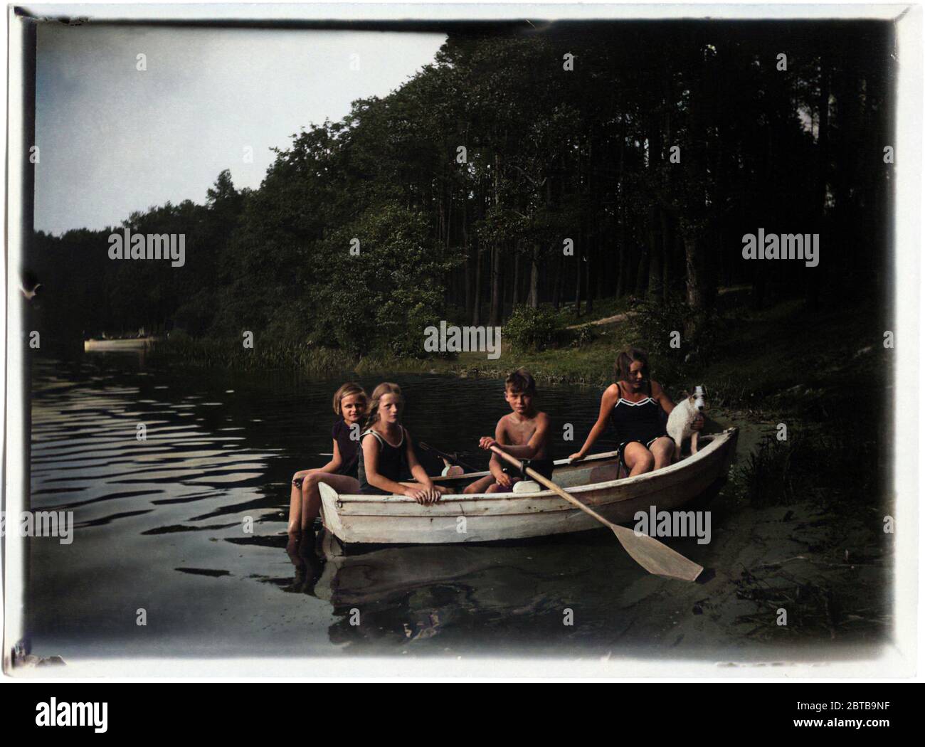 1930 c,ALLEMAGNE : Quatre enfants avec un chien sur un barque dans un étang . Photo par undentifiend photographe amateur allemand, COLORISÉ NUMÉRIQUEMENT . - VACANCES - VACANCES - VACANCES - lago - FOTO STORICHE - PHOTOS D'HISTOIRE - BAMBINO - BAMBINI - ENFANTS - ENFANT - BÉBÉ - ENFANCE - INFANZIA - ANNI TRENTA - '30 - 30's - gioia - glee - joie - joie - joie - joie - joie - joie - joie - plaisir - divertimento - Plaisir - ÉTÉ - DOMAINE - albero - soutien - alberi - bosco - buisson - canne - chien animal - barca a remi -- Archivio GBB Banque D'Images