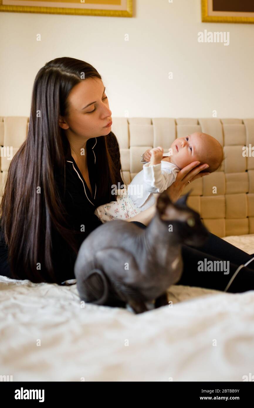 Sphynx chat est assis près de la mère et bébé tout-petit sur un lit blanc Banque D'Images