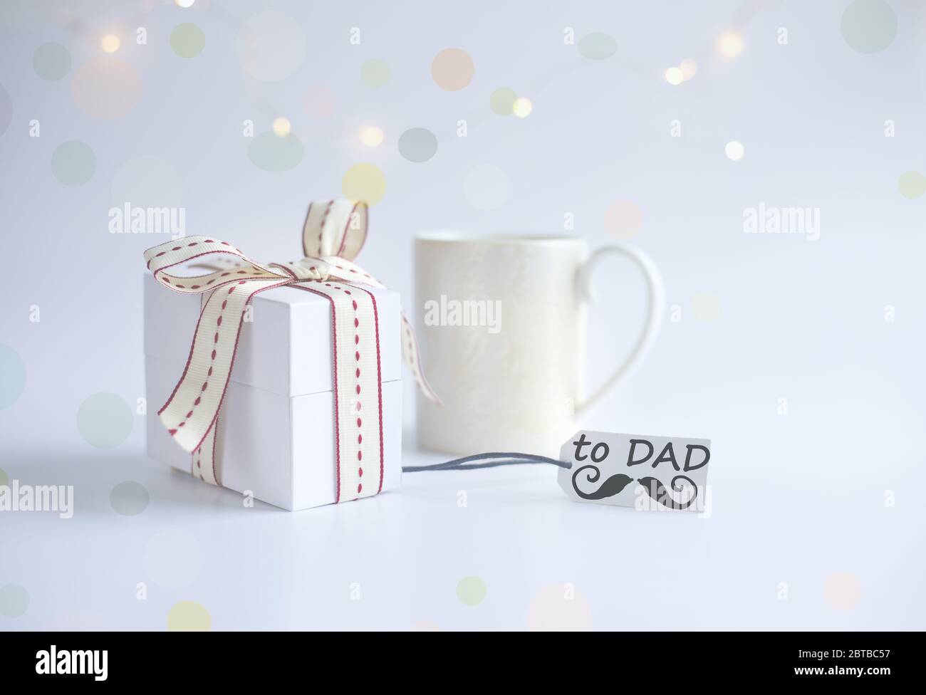 Tasse de café du matin, boîte cadeau emballée, étiquette cadeau avec mot DAD et icône de moustache sur fond clair avec bokeh Banque D'Images