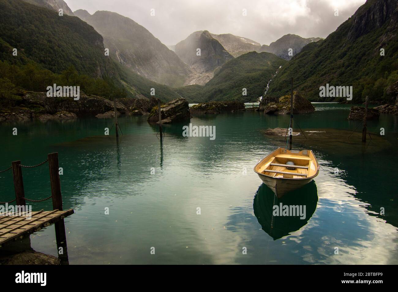 Paysage pittoresque incroyable montrant le lac Bondhus avec un petit bateau et son ombre et quelques montagnes en Norvège Banque D'Images