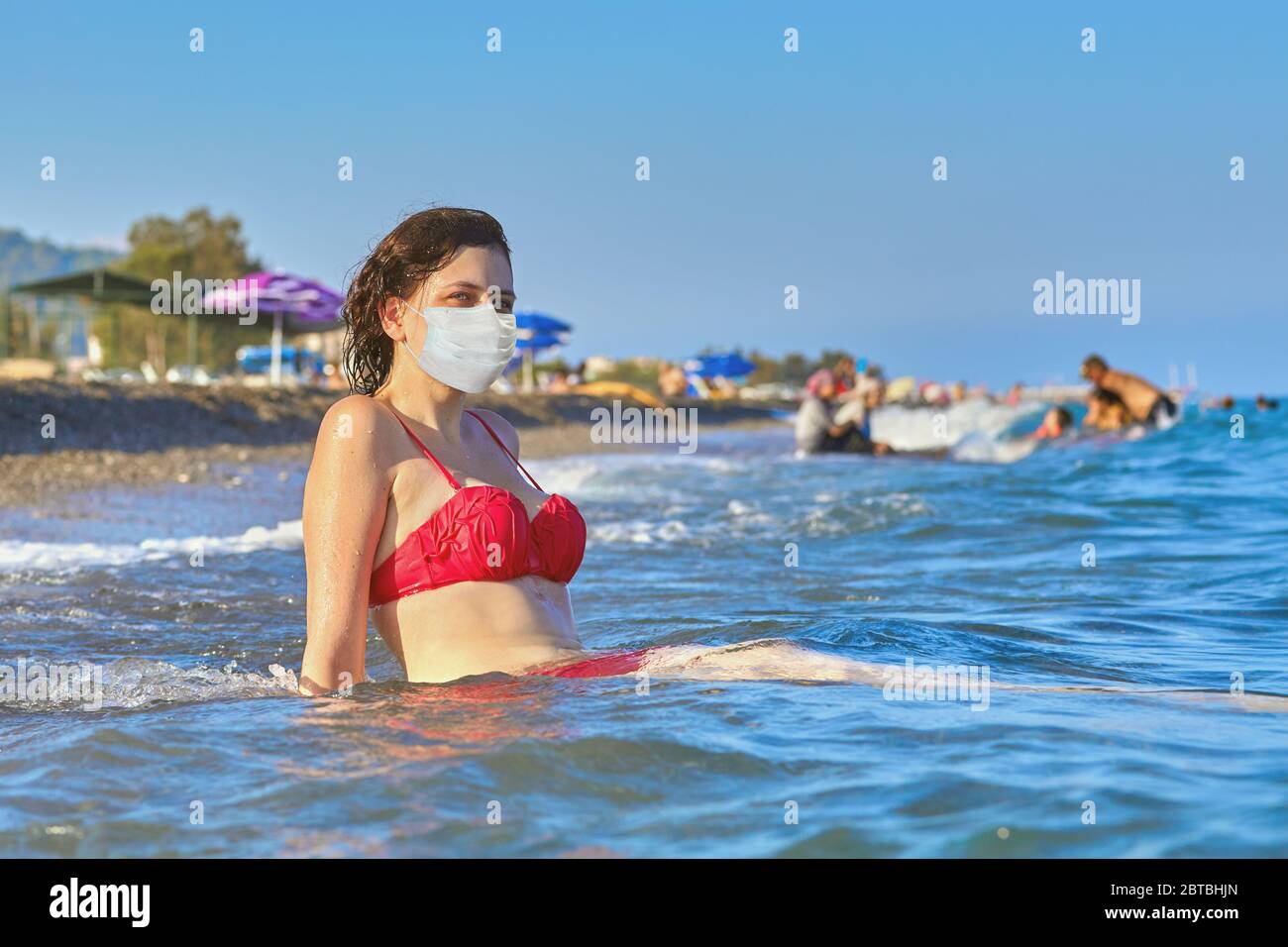 Jeune belle femme caucasienne en maillot de bain rouge avec masque  chirurgical de protection du visage desposable sur son visage comme une  protection contre l'infection de covid-19 est Photo Stock - Alamy