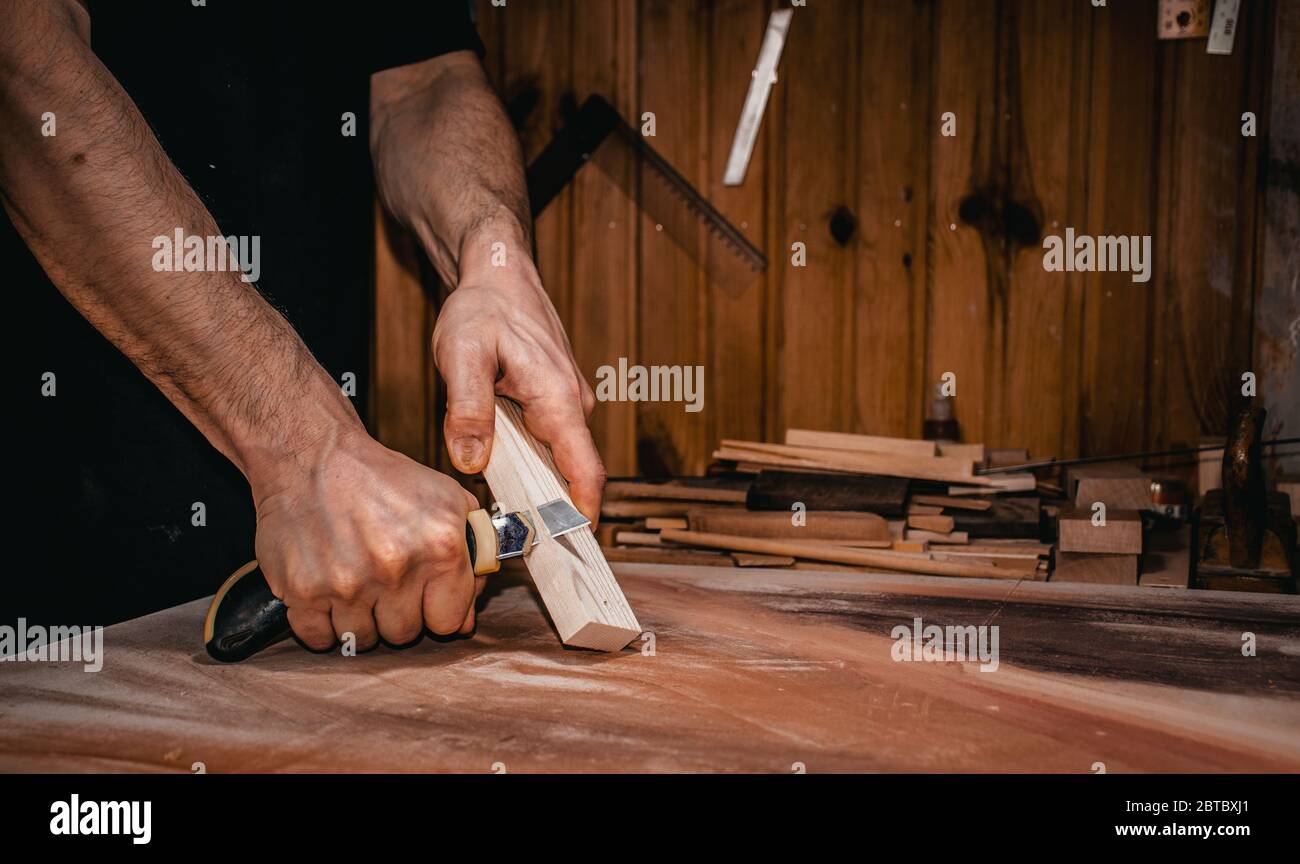 un homme qui coupe un morceau de bois avec un couteau utilitaire, mains seulement, scène de gros plan. Banque D'Images
