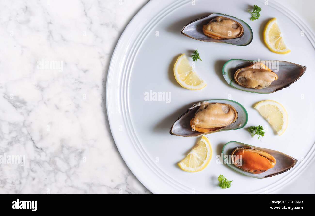 Moules néo-zélandaises avec tranches de citron et de persil, sur un plat blanc Banque D'Images