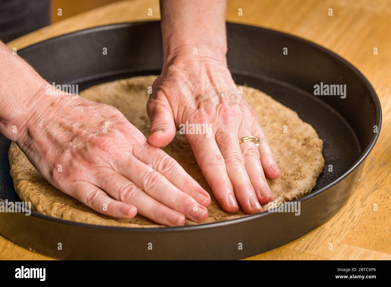 Une fois que la pâte à pizza a été étirée autant que possible dans l'air, aplatissez-la avec vos mains, en commençant au centre et en travaillant vers l'extérieur, utilisez y Banque D'Images