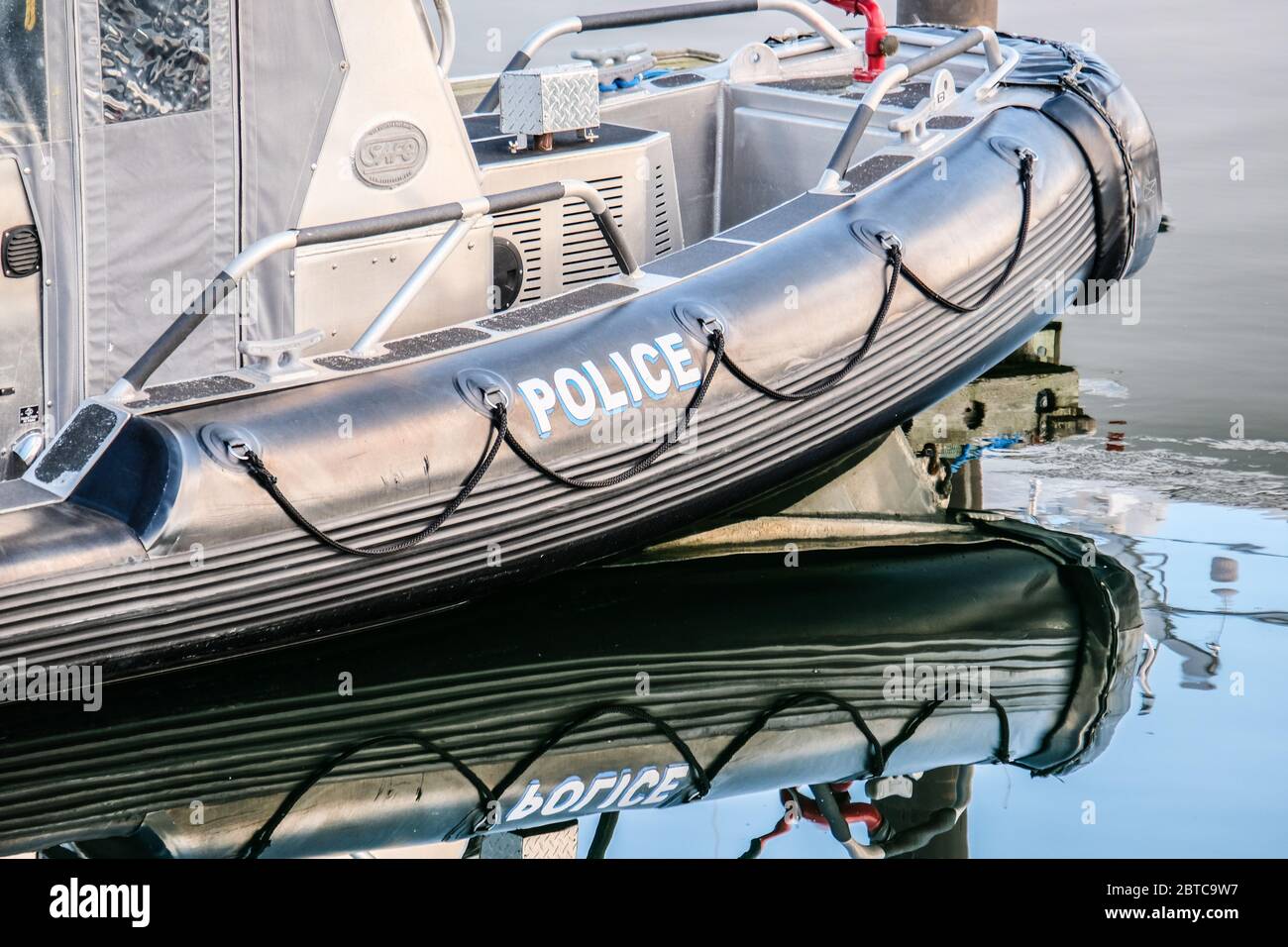 Un bateau gonflable de police Zodiac sur un quai avec réflexion dans l'eau Banque D'Images