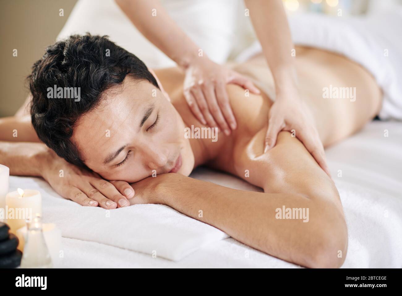 Masseuse donnant un massage profond du dos et des épaules au jeune homme Banque D'Images