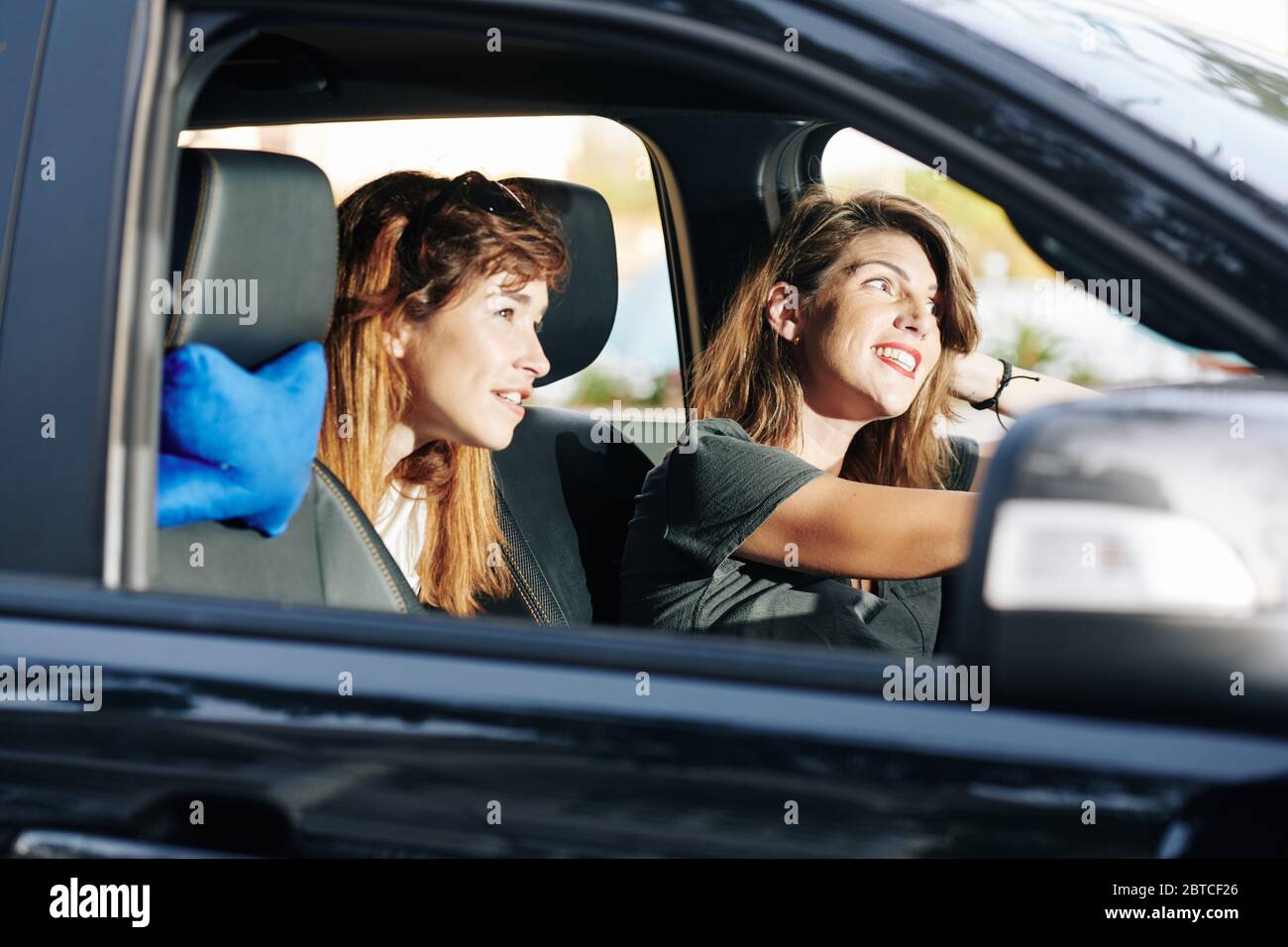 Des amies joyeuses, qui apprécient la voiture et parlent bien le dimanche Banque D'Images