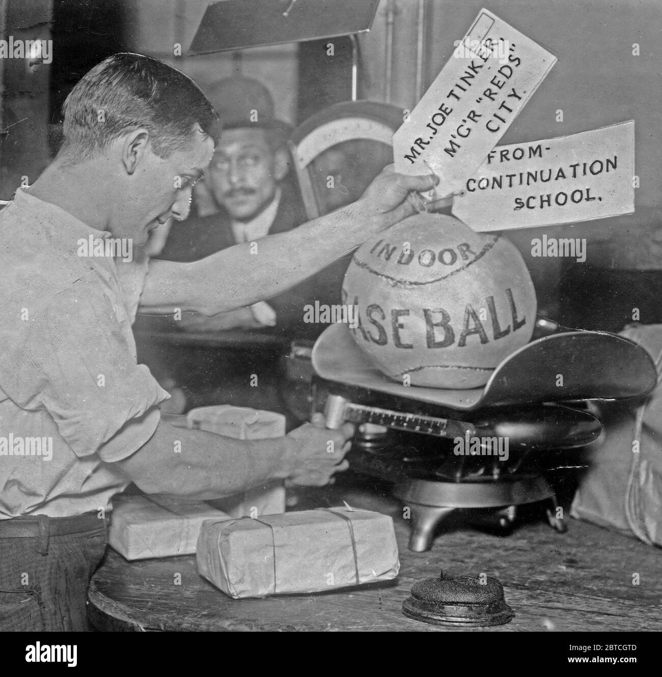 Le ballon de médecine étant pesé par l'employé de poste; étiquettes d'expédition lire: M. Joe Tinker, Mgr Reds (Cincinnati) de la continuation School Banque D'Images