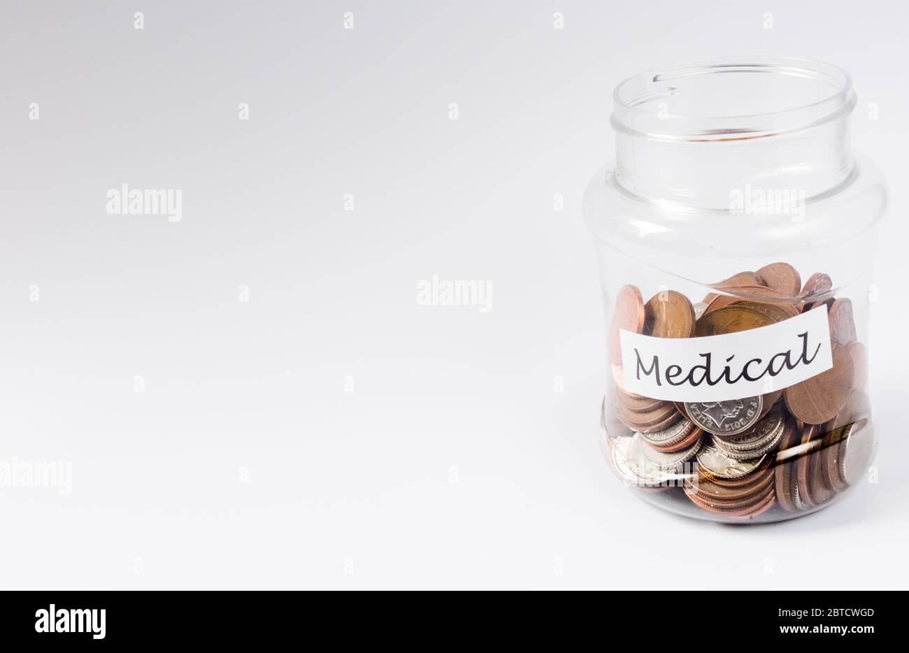 Frais médicaux économisant des centimes dans un pot à pièces transparent Banque D'Images