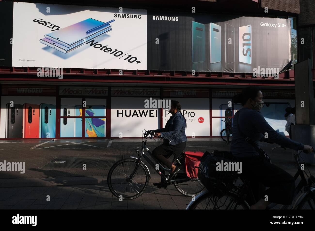 Les gens font un tour de vélo devant un magasin électronique avec des annonces de la marque chinoise de télécommunications les smartphones P30 Pro de Huawei et les smartphones Galaxy Note 10 et S10 de Samsung Electronics Co. En Corée du Sud, le 21 mai 2020 à la Haye, pays-Bas. Crédit: Yuriko Nakao/AFLO/Alay Live News Banque D'Images