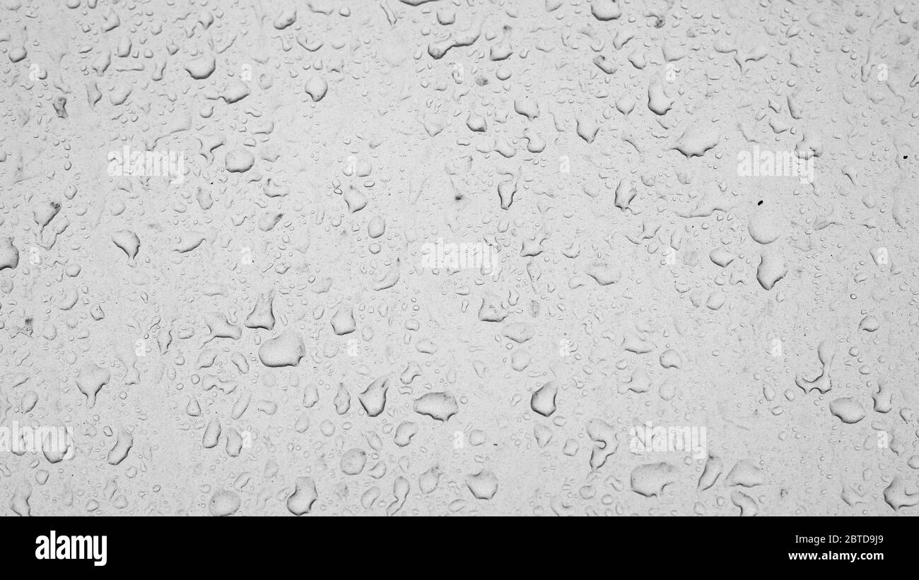 gouttes de pluie sur la vitre de la voiture, la texture de l'eau tombe sur une fenêtre poussiéreuse. Fond d'écran à effet texturé, toile de fond, temps de pluie noir et blanc Banque D'Images