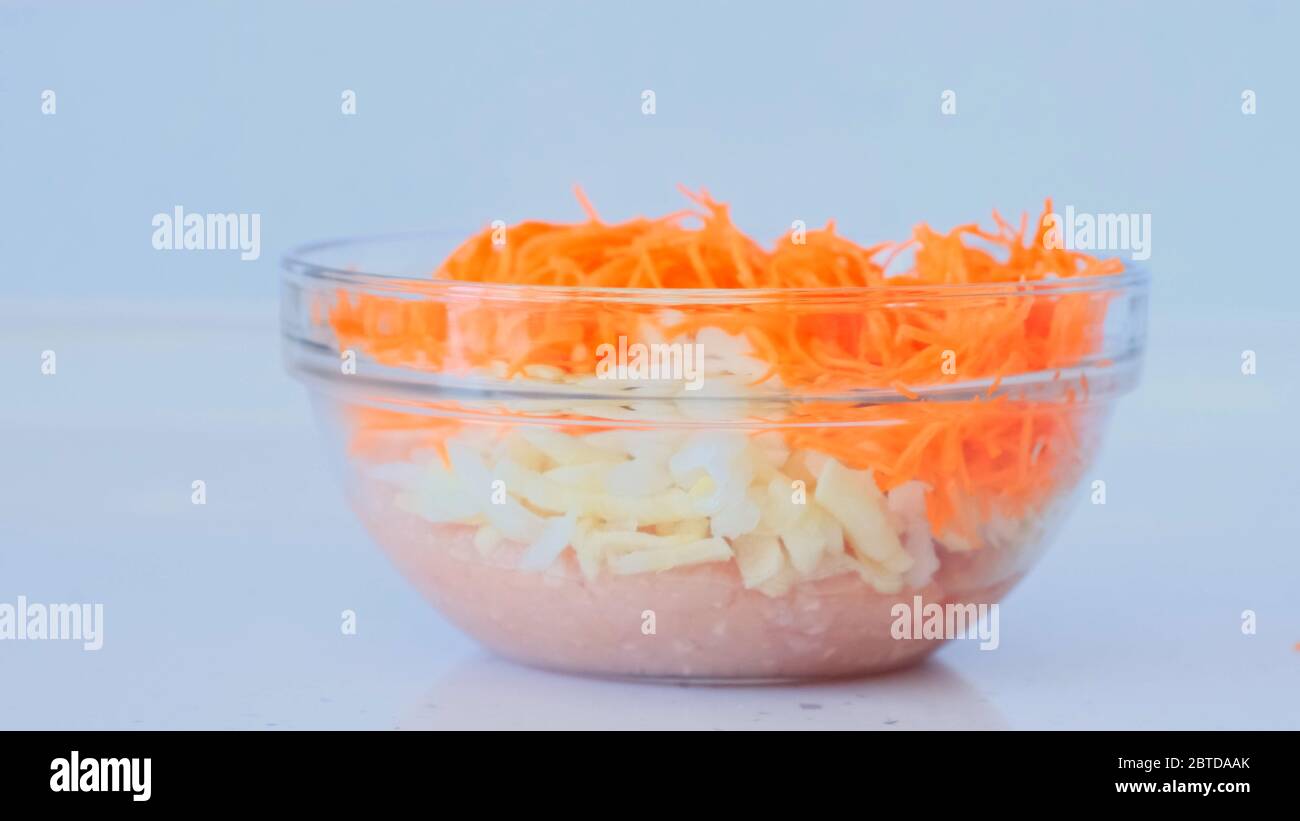 La fille prépare de la viande hachée. La main féminine ajoute des carottes, des oignons à la viande hachée et mélange. Plats à base de viande Banque D'Images