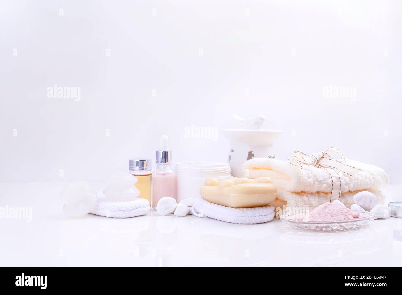 Spa détente et concept de bain, sel de mer, savon, avec cosmétiques et serviettes sur fond blanc. Une serviette en coton doux, du savon, de la crème, du sel de mer et une éponge pour le lavage. Mise au point programmable . espace pour le texte. Banque D'Images