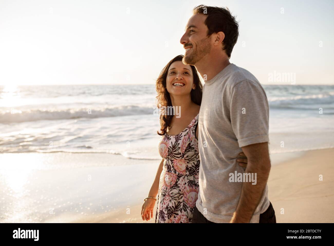 Un jeune couple aimant se promenant ensemble le long d'une plage de sable Banque D'Images