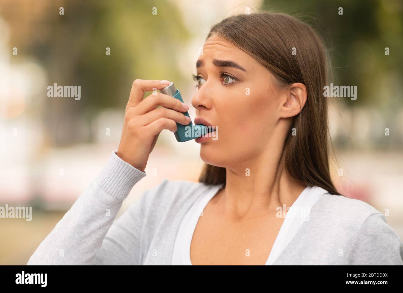 Femme ayant une attaque asthmatique utilisant Inhaler Standing Outdoor Banque D'Images