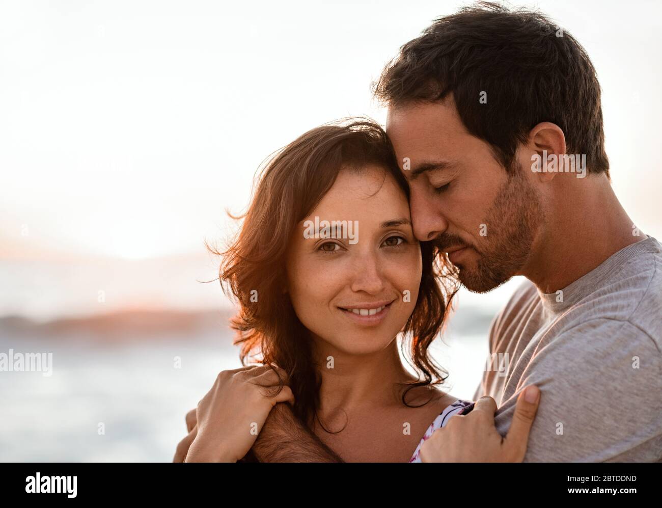 Jeune femme souriante debout dans les bras de son mari sur une plage Banque D'Images