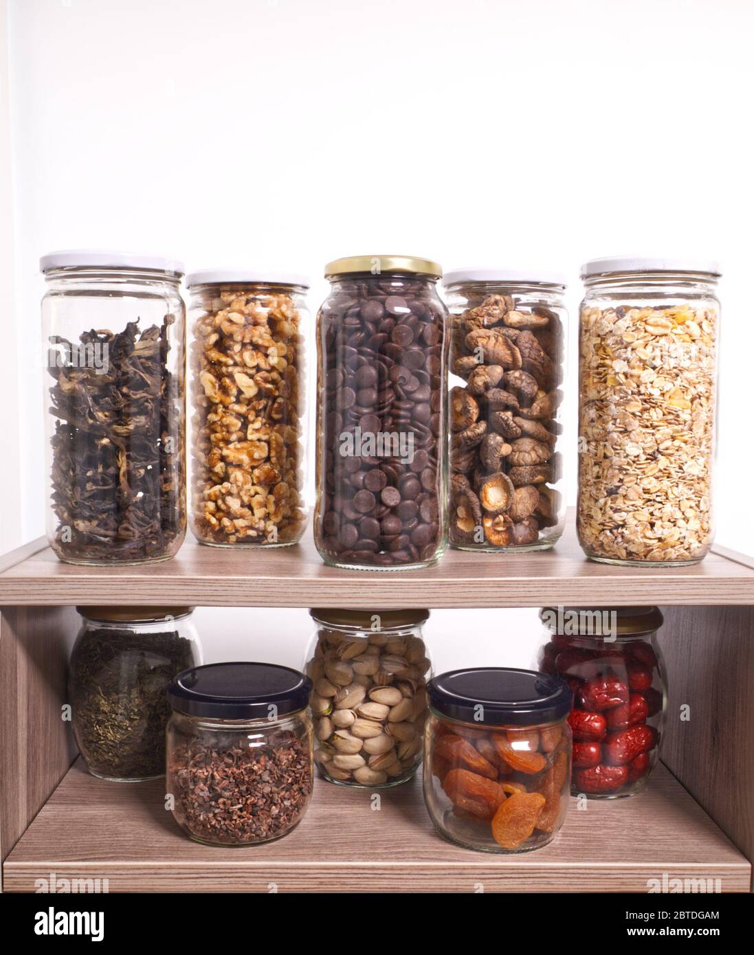 Aliments en vrac stockage dans des pots en verre : champignons sauvages secs, muesli, chocolat, noix, dattes, pistaches, herbes aromatiques. Concept zéro déchet. Banque D'Images