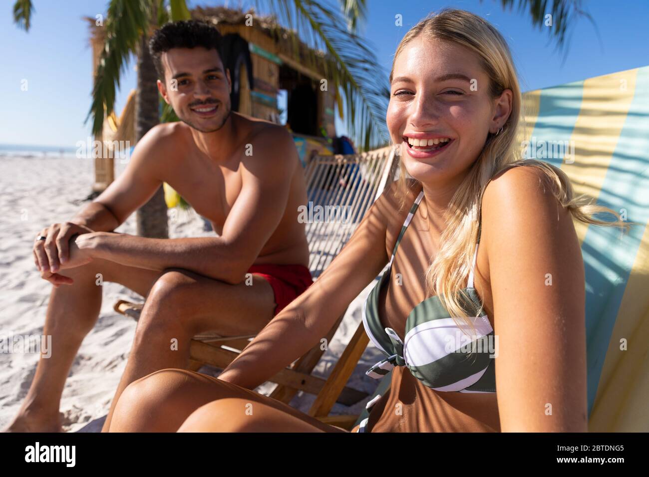 Couple caucasien assis sur des chaises longues à la plage Banque D'Images