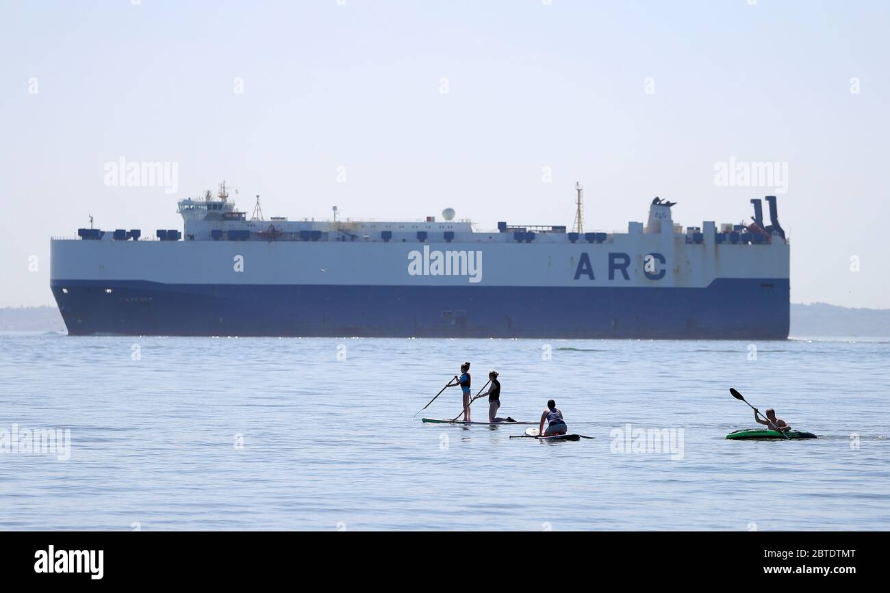 Southampton, Hampshire, Royaume-Uni. 25 mai 2020. Météo Royaume-Uni. Un transporteur de voitures passe devant les amateurs de plage de Calshot Beach en route vers les quais de Southampton. Credit Stuart Martin/Alay Live News Banque D'Images