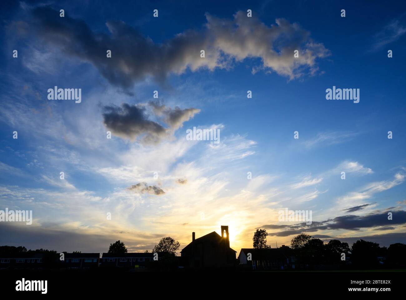 Des nuages spectaculaires au coucher du soleil sur l'église St Johns à Beckenham, Kent, Royaume-Uni. Le soleil couchant brille à travers le clocher de l'église avec un ciel magnifique. Banque D'Images