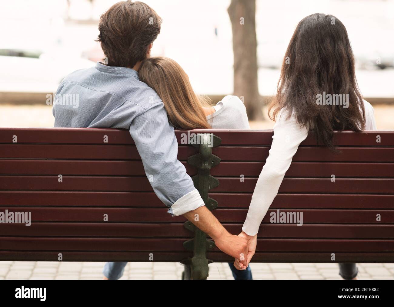 Petit ami tenant les mains avec l'ami de petite amie assis sur un banc extérieur Banque D'Images