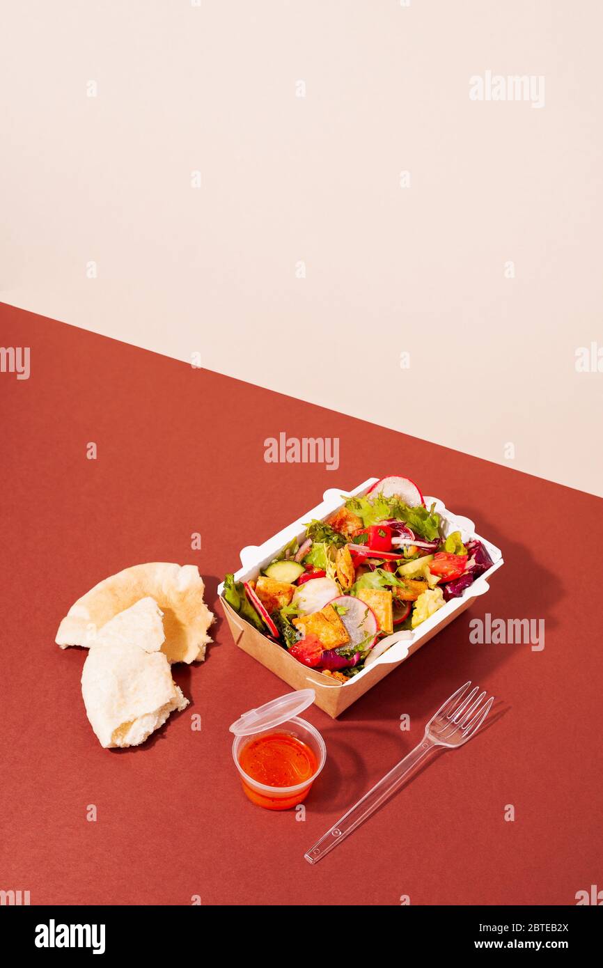 Salade de fattoush végétarienne saine et fraîche dans un emballage à emporter sur fond rouge et beige. Restaurant de livraison concept de cuisine authentique Banque D'Images
