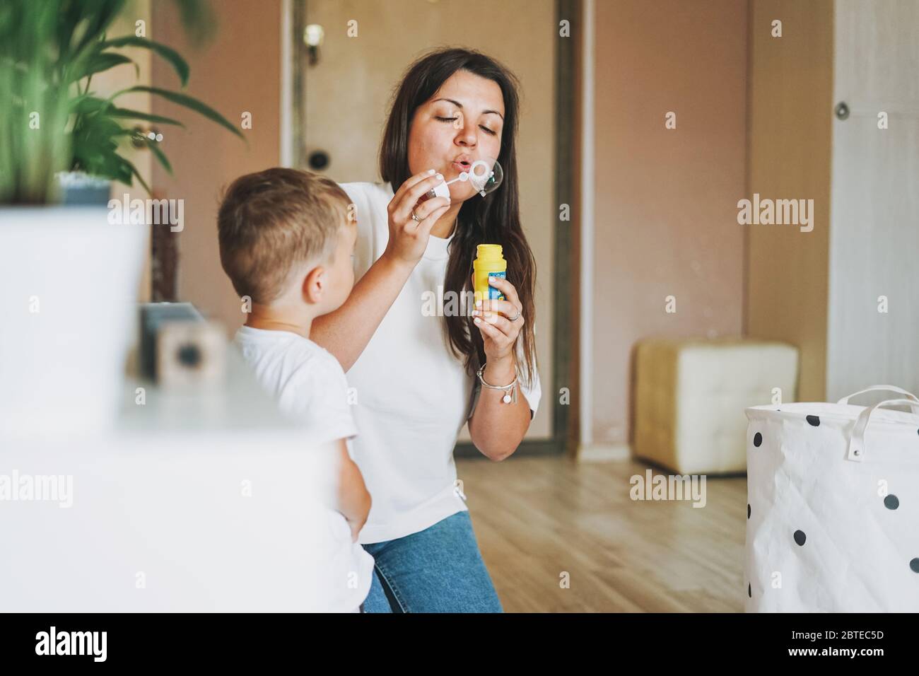 Un joli petit garçon avec une mère qui soufflait de bulles de savon à la maison Banque D'Images