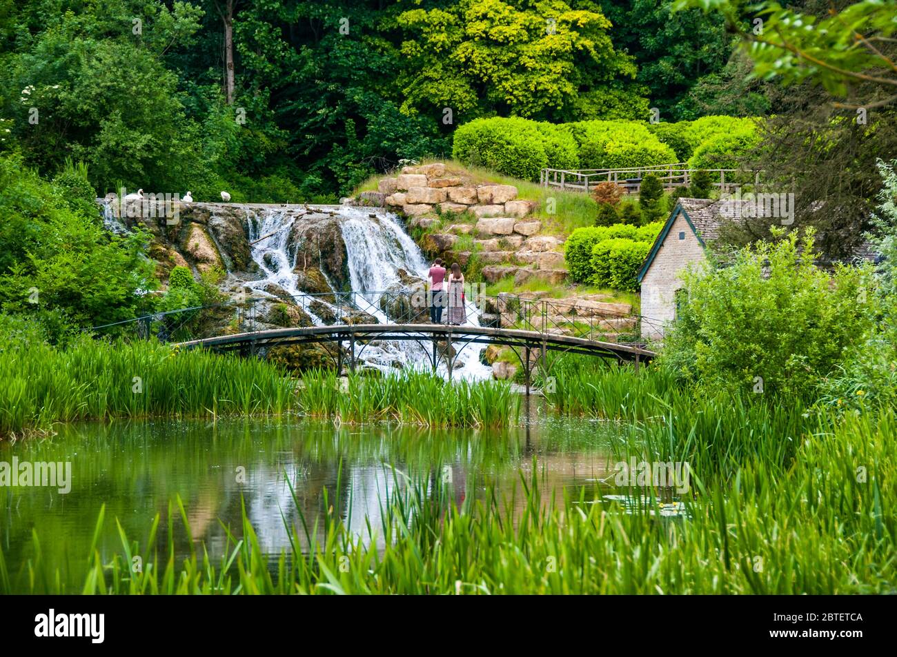 Un couple sur un pont en face du Grand Cascades dans les jardins de Blenheim Palace, Oxfordshire, Angleterre. Banque D'Images