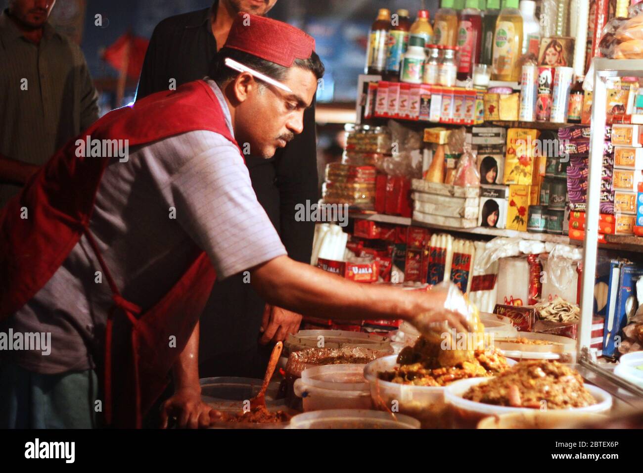 Vendeur portant le chapeau sindhi vendant l'achaar à saddar bazar karachi, Pakistan 15/03/2013 Banque D'Images