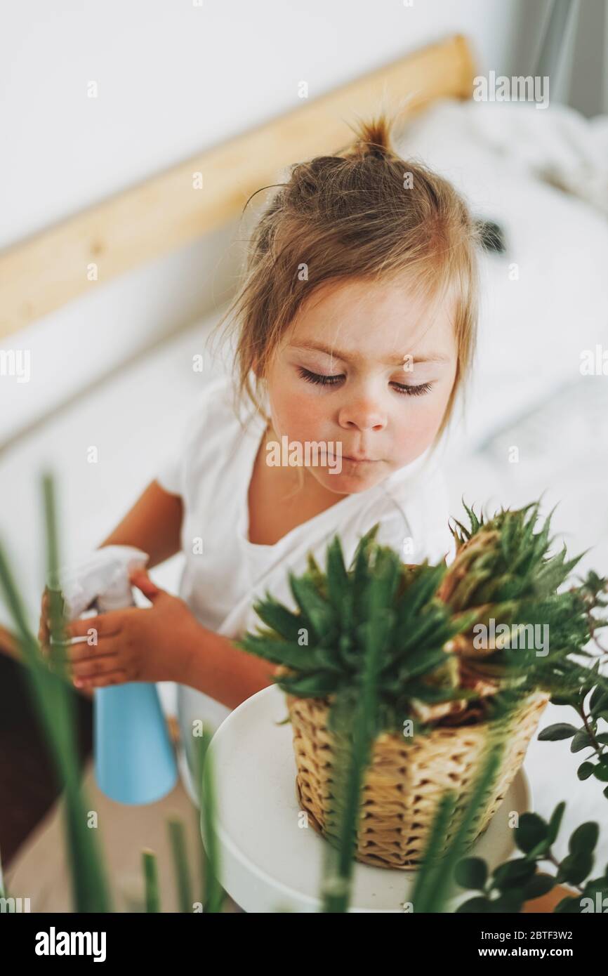 Drôle de petite fille arrosoir plante maison à la chambre dans la maison intérieure lumineuse Banque D'Images