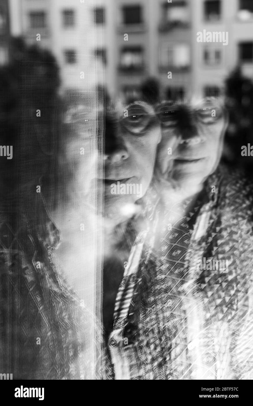 Image originale noire et blanche triste avec la vieille femme fermer la fenêtre en temps de virus corona. Barcelone, Espagne. Banque D'Images
