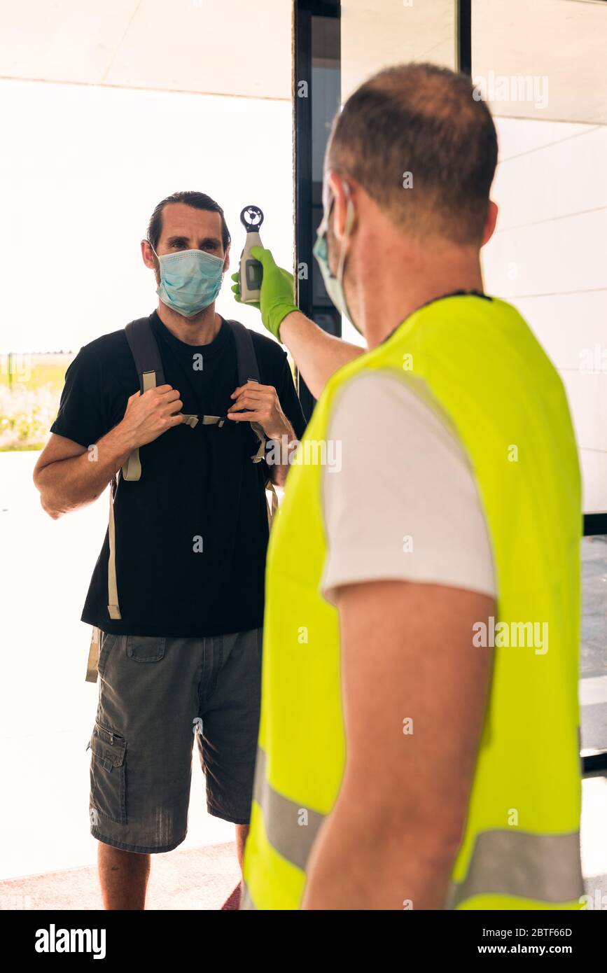 Concept : nouvelle normalité. Coronavirus, covid-19. Homme de sécurité prenant la température d'une autre personne avec un thermomètre. Contrôle d'entrée d'un bâtiment. PA Banque D'Images