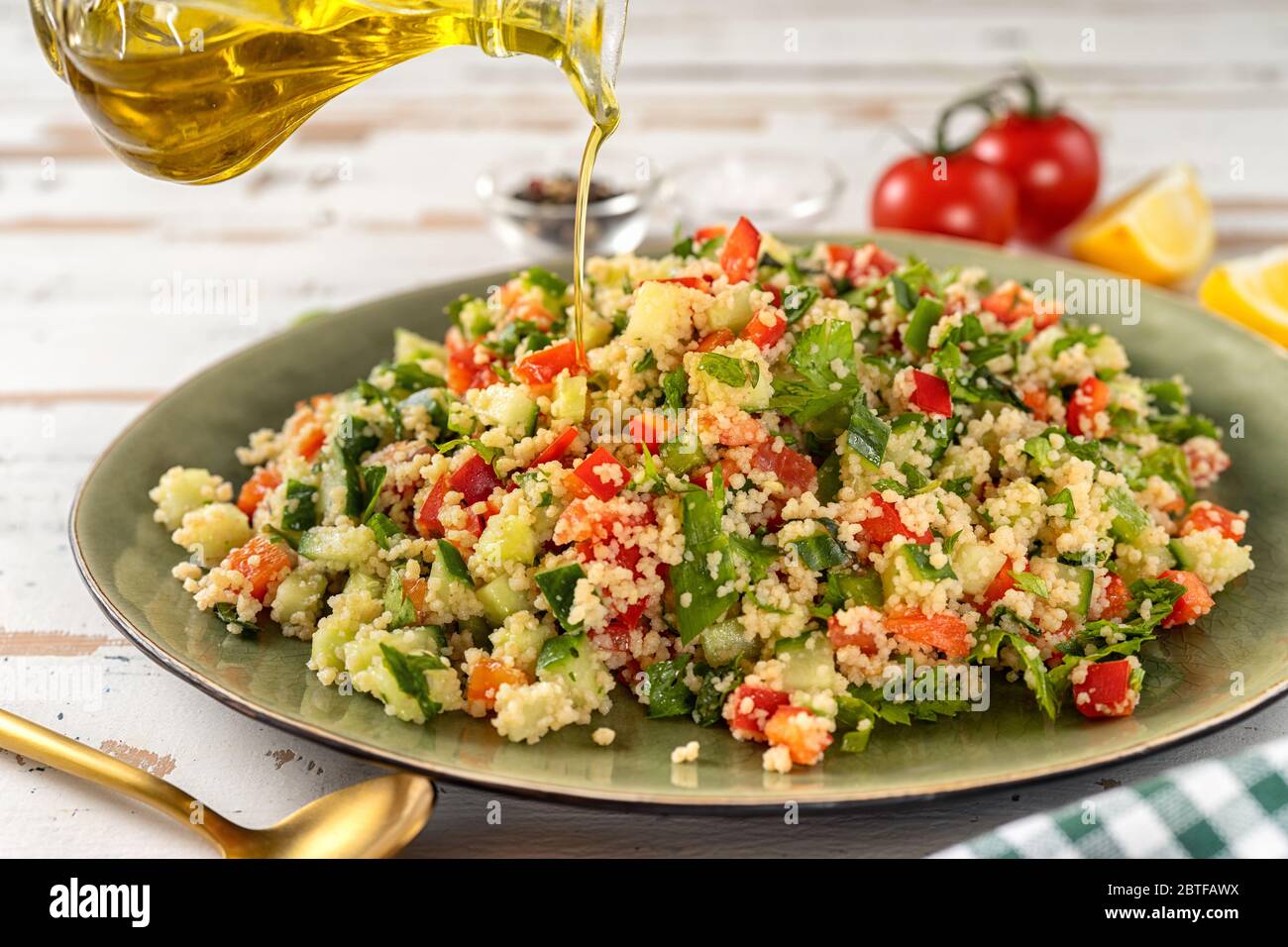 Verser une huile d'olive dans une grande assiette de légumes salade de couscous frais Banque D'Images